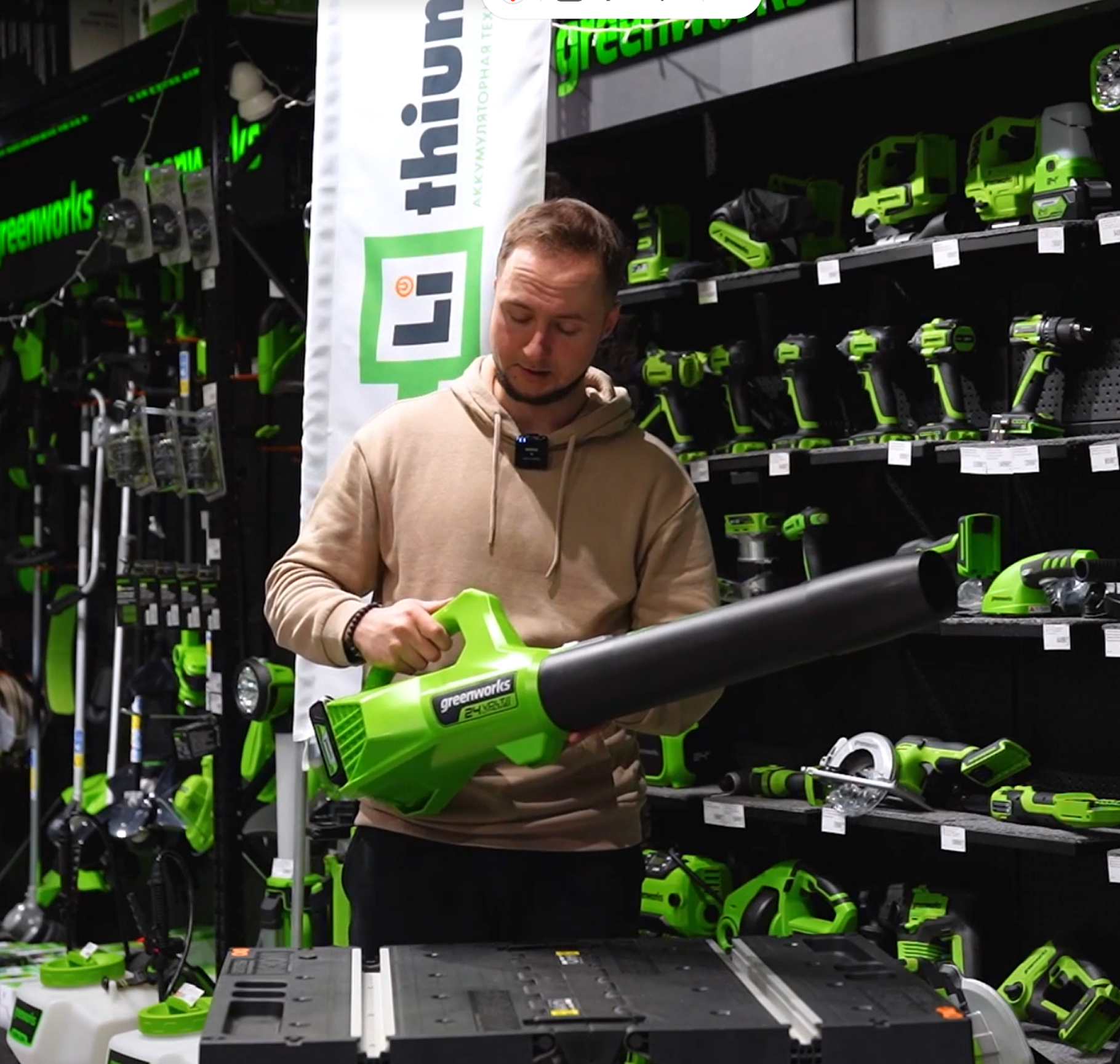 Консультант магазина Greenworks демонстрирует аккумуляторную воздуходувку в торговом зале